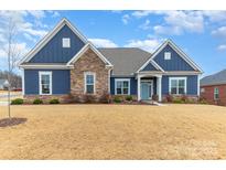 Charming blue single-Gathering home featuring stone accents, a manicured lawn, and a welcoming light-blue front door at 1203 Kingsman Nw Ln, Concord, NC 28027