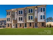 View of new construction townhomes featuring brick facade, modern design, and green lawn at 1311 Cerium Way, Charlotte, NC 28211