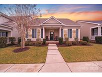 Charming single-story home features manicured lawn, welcoming porch, and stylish shutters at sunset at 11135 Bailey Park Nature Dr, Cornelius, NC 28031