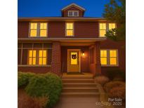 Charming two-story brick home with inviting front porch and illuminated windows at dusk at 113 2Nd St, Spencer, NC 28159