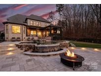 A gorgeous backyard featuring a patio, pool with waterfall, putting green, and fire pit, perfect for outdoor entertaining at 17639 Stuttgart Rd, Davidson, NC 28036