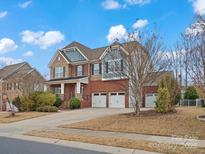 Beautiful two-story home with a brick facade, three-car garage, and manicured lawn on a sunny day at 3813 Litchfield Dr, Waxhaw, NC 28173