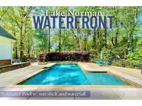 Lake Norman waterfront home featuring a saltwater pool with sun shelf and waterfall feature at 8384 Blades Trl, Denver, NC 28037