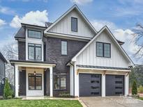 Striking new construction featuring a black brick facade, white accents, and a spacious three-car garage at 919 Laurel Creek Ln, Charlotte, NC 28211