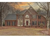 Stately two-story brick home featuring a manicured lawn and traditional architectural details at dusk at 2800 Providence Hills Dr, Matthews, NC 28105