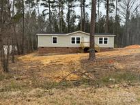 Charming ranch home with neutral siding, brick foundation, wooden deck, and a backdrop of tall trees at 339 Pine Lake Dr # 760, Troy, NC 27371