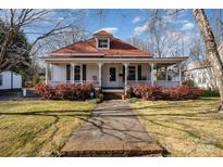 Charming home with a red roof, white siding, and a welcoming front porch, surrounded by lush greenery at 517 Stockton St, Statesville, NC 28677