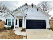 Charming home featuring a black garage door, a welcoming front door with a wreath, and well-maintained landscaping at 713 E Third Ave, Gastonia, NC 28054