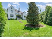 Expansive backyard featuring lush green lawn, mature trees, and a charming white brick home at 1328 S Kings Dr, Charlotte, NC 28207