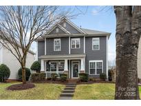 Charming two-story home with gray siding, white trim, covered porch, and well-manicured landscaping at 17436 Harbor Walk Dr, Cornelius, NC 28031