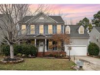 Charming two-story home featuring gray siding, blue shutters, a landscaped front yard and attached garage at 1245 Periwinkle Dr, Waxhaw, NC 28173
