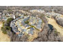 An aerial view shows a neighborhood with brick homes, a golf course, ponds, and mature trees in a suburban setting at 4008 Saint Andrews Ct, Cramerton, NC 28032