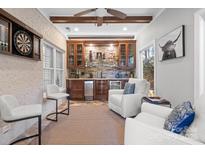 Entertaining space featuring a bar with custom cabinetry, mini-fridge, stone backsplash, and comfortable seating at 4008 Saint Andrews Ct, Cramerton, NC 28032
