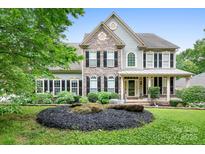 Charming two-story home featuring stone accents, black shutters, and a beautifully landscaped front yard at 7191 Grist Mill Ct, Denver, NC 28037