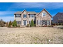 Charming two-story home featuring a stone and vinyl facade, black shutters, and a well-manicured front yard at 8471 Penton Pl, Harrisburg, NC 28075