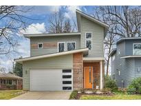 Contemporary two-story home featuring a stylish orange front door, white garage door, and unique architectural details at 3126 Creighton Dr, Charlotte, NC 28205