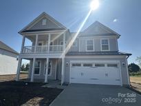 Charming two-story home with a welcoming front porch and attached two-car garage, bathed in sunlight at 3213 Mcharney Dr # 32, Harrisburg, NC 28075