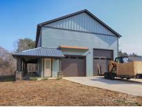 View of the attractive blue two-story home with a covered porch and large garage doors at 3528 Thunder Rd, Maiden, NC 28650