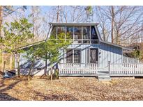 Charming home with a sloped glass roof and a welcoming front porch, nestled among mature trees at 5082 Mariana Ct, Tega Cay, SC 29708