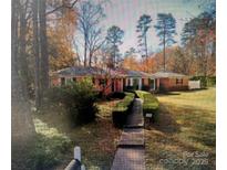 Charming brick home with a manicured front yard and walkway, nestled among mature trees at 5600 Riviere Dr, Charlotte, NC 28211