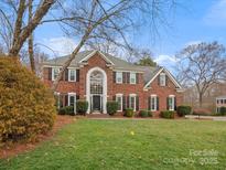 Stately brick home with a manicured lawn and classic architectural details including a soaring window above the front door at 9743 Aegean Ct, Huntersville, NC 28078
