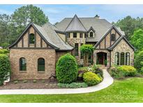 Stunning two-story home with a turret, brick and stone facade, professional landscaping and a winding walkway to the front door at 16824 Ashton Oaks Dr, Charlotte, NC 28278