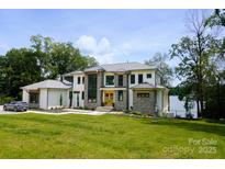 Stunning modern home with stone accents, manicured lawn, and lush trees create an inviting curb appeal at 180 Willow Point Rd, Troutman, NC 28166