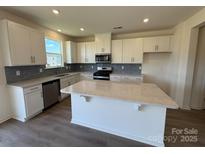 Bright kitchen boasts white cabinets, stainless appliances, gray backsplash and a large center island at 330 Knotty Wood Dr # 67, Monroe, NC 28110
