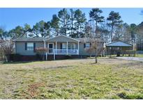 Charming single-story home features a covered front porch and a convenient carport, set against a backdrop of mature trees at 3640 Muskrat Se Pl, Concord, NC 28025