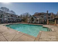 Community pool featuring a clear blue swimming pool, a bath house, and surrounding apartment buildings on a sunny day at 5009 Sharon Rd # E, Charlotte, NC 28210