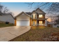 Charming two-story home featuring a brick and siding exterior, a two-car garage, and a cozy front porch at 7500 Grabill Dr, Charlotte, NC 28269