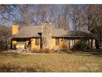 Charming single-story home with yellow siding, a stone chimney, and a well-manicured front yard at 8133 Strawberry Ln, Charlotte, NC 28277