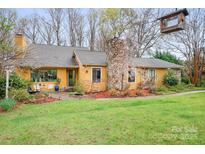 Charming single-Gathering home featuring a stone chimney, mature landscaping, and inviting front entrance at 8133 Strawberry Ln, Charlotte, NC 28277