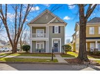 Charming two-story home with a inviting covered porch and balcony, a beautiful yard, and a classic blue door at 14462 Holly Springs Dr, Huntersville, NC 28078