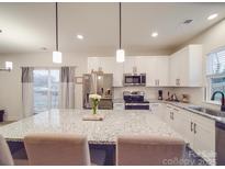 Bright kitchen features a large island with granite countertops, stainless steel appliances, and white cabinetry at 711 E 3Rd Ave, Gastonia, NC 28054