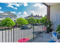 Balcony view overlooking charming street lined with mature trees and nearby buildings under a sunny, partly cloudy sky at 5380 Village Dr # 203, Concord, NC 28027