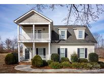Charming two-story home with a covered porch, balcony, and well-manicured landscaping at 662 Georgie St, Troutman, NC 28166