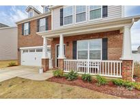 Charming two-story home with a brick facade, white porch, and attached two-car garage at 9203 Mackinaw Dr, Gastonia, NC 28056