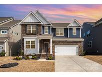Stately two-story home boasts a brick and siding exterior, attached garage, and manicured landscaping at 1051 Lookout Shoals Dr, Fort Mill, SC 29715