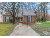 Charming brick home features blue shutters, mature trees and a neatly manicured front yard at 11127 Sevilla Ct, Charlotte, NC 28226