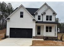 Charming two-story white home featuring a black garage door, black trim, and a welcoming front porch at 157 Powder Spring Dr, Statesville, NC 28677