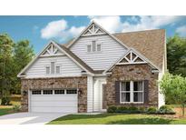 Charming two-story home featuring stone and white siding accents, a two-car garage and a well-manicured lawn at 1047 Rabbit Hill Ln, Monroe, NC 28110