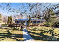 Charming brick home with a blue metal roof, blue shutters, and mature landscaping at 1552 10Th Street Nw Pl, Hickory, NC 28601