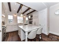 Well-lit kitchen with white cabinetry, marble countertops, a central island, and dark hardwood floors at 3064 Selwyn Ave, Charlotte, NC 28209