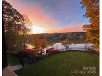 Beautiful sunset over the lake, trees in fall colors, green grass, and black aluminum fence at 649 46Th Avenue Ne Dr, Hickory, NC 28601