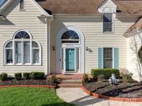 Close up view of a home's front door with turquoise shutters and manicured garden beds at 10700 Summitt Tree Ct, Charlotte, NC 28277