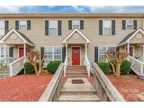 Inviting townhome featuring neutral siding, black shutters, a red front door, and attractive landscaping at 1469 Flintwood Dr, Rock Hill, SC 29732