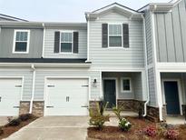 Charming townhome featuring a one-car garage, craftsman-style details, and a beautifully landscaped front yard at 1758 Braemar Village Dr, Monroe, NC 28110