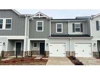 Charming two-story townhome featuring gray siding, a one-car garage, and well-maintained landscaping at 1760 Braemar Village Dr, Monroe, NC 28110