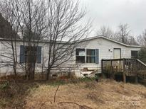 Exterior view of house with a weathered facade, simple deck, and a 'For Sale' sign at 206 Bonnie Ln, China Grove, NC 28023